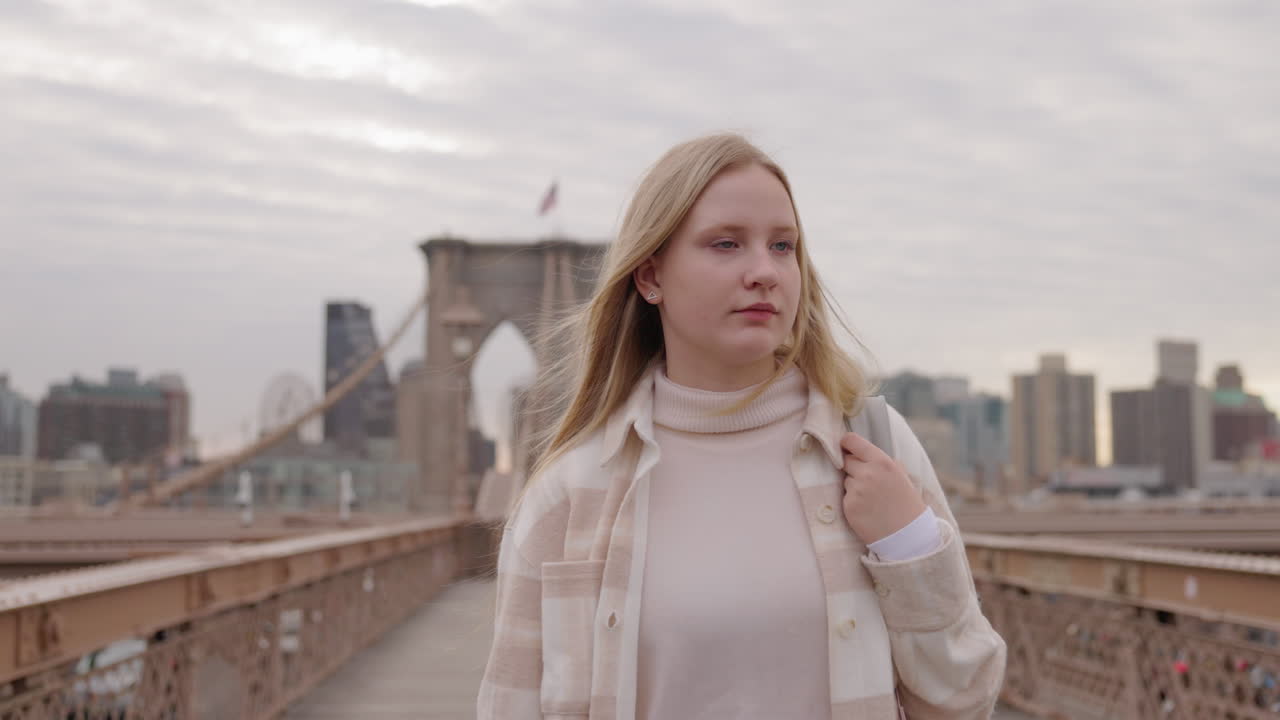 Młoda kobieta z plecakiem na Moście Brooklińskim z panoramą Manhattanu w Nowym Jorku.