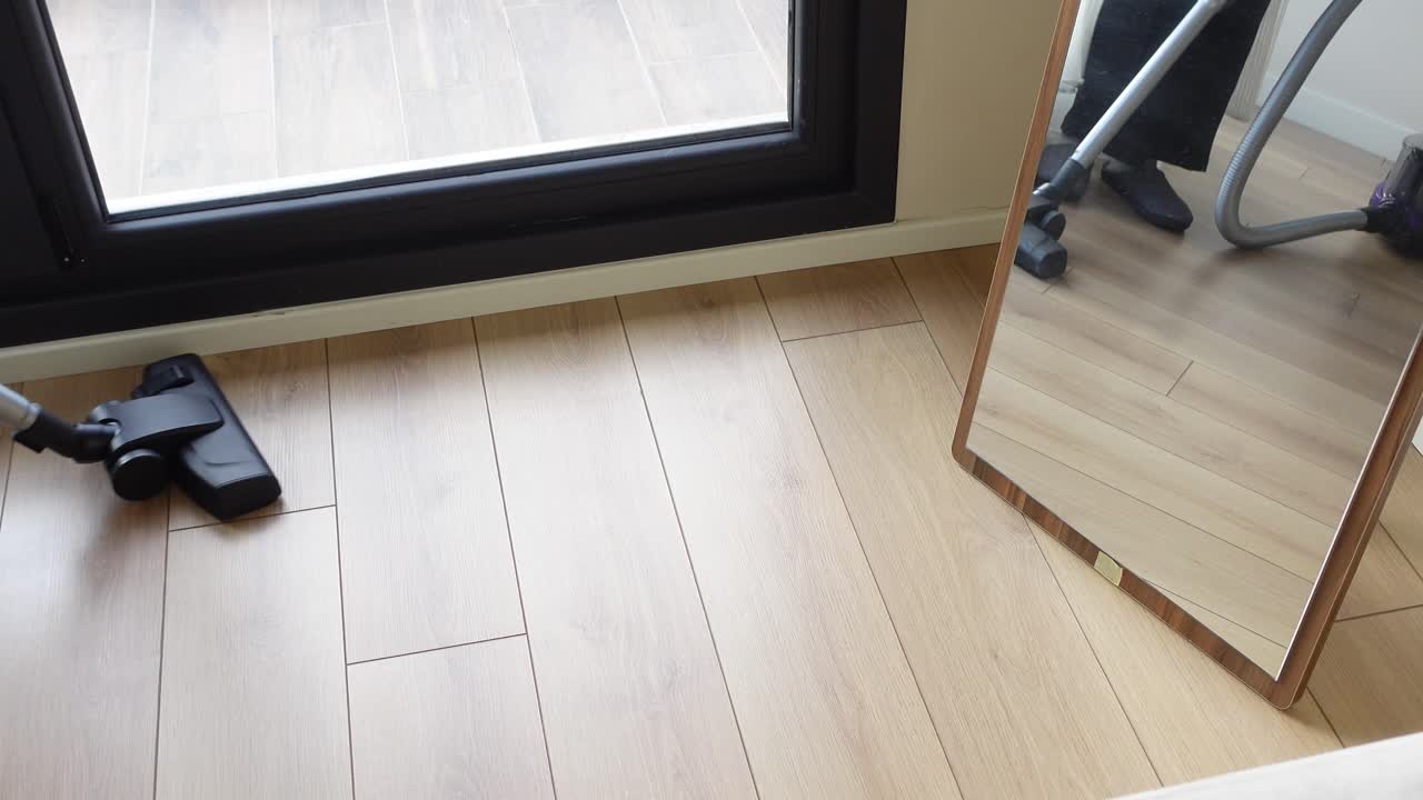 Person vacuuming a wooden floor