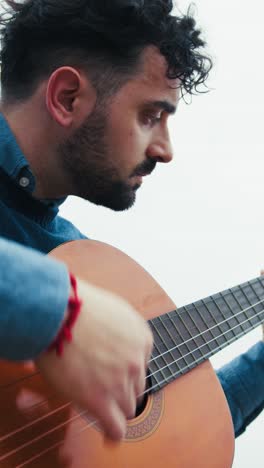 man practices arpeggios on guitar while playing outdoors
