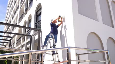man installing security camera on building wall