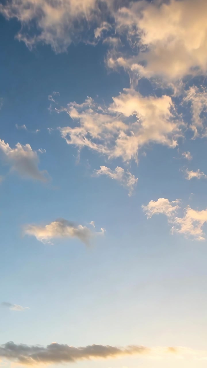 Video verticale: Ammasso di cumuli alla deriva sotto la luce mutevole del tramonto nel cielo, con il bagliore dell'orizzonte