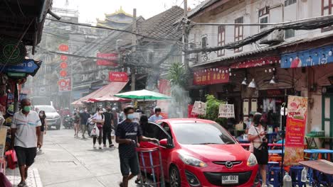 red car driving through a busy market street