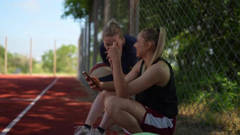 two women relaxing on court with basketball