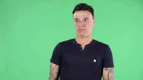 retrato de un joven guapo mira a su alrededor está diciendo oops y confundido. pantalla verde
