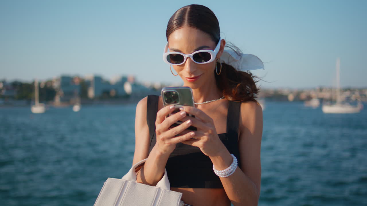 Donna elegante che usa il telefono in riva all'oceano