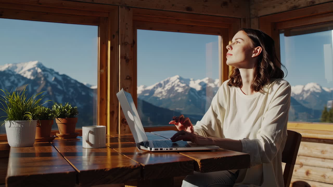 Woman working remotely from a rustic cabin with stunning mountain views