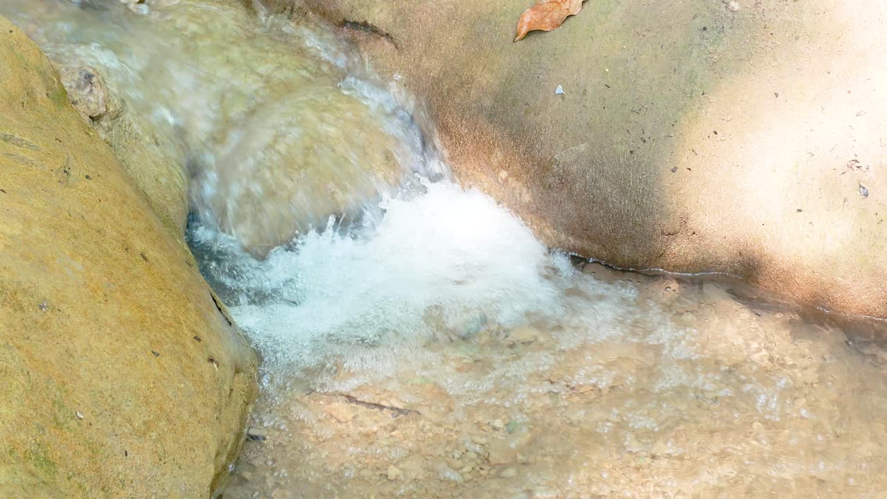 조용한 폭포가 바위 위로 흐르고, 자연적인 조명 속에 포착되어 평화로운 야외 환경의 아름다움을 보여줍니다.