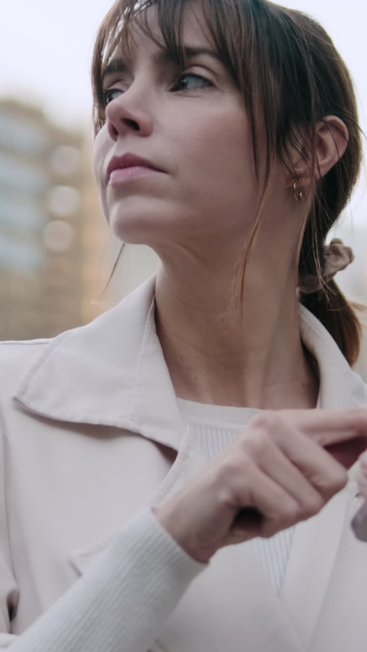 Giovane donna che scorre lo smartphone e guarda in alto all'aperto