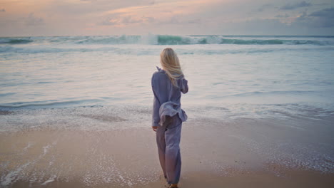 relaxed lady enjoying coast evening. happy blonde walking sandy shore on sunset