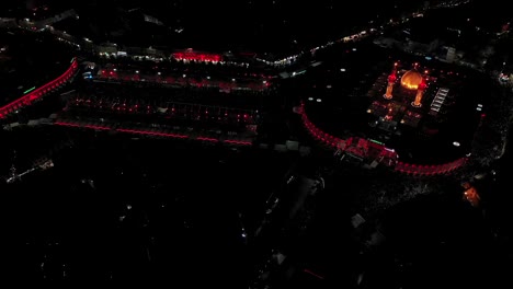 Una-Foto-Nocturna-Tomada-Por-Un-Dron-De-Visitantes-Y-Peregrinos-Chiítas-En-La-Mezquita-Y-El-Santuario-Del-Imam-Hussein-Y-Abbas-En-Karbala,-Irak.