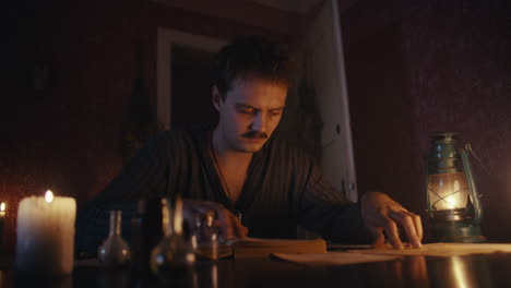 man studying by candlelight and lantern