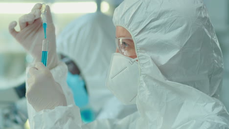 lab worker in protective coverall suit and mask doing research