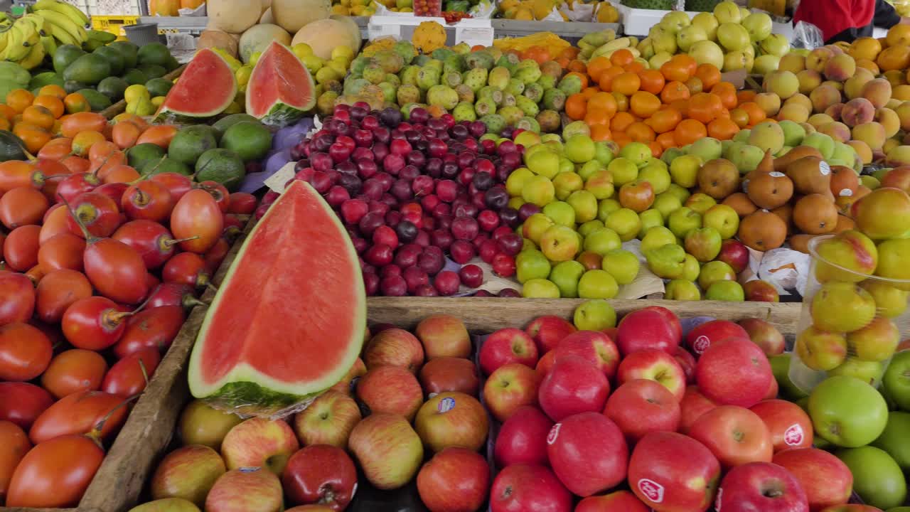 Primer plano panorámico de frutas variadas cuidadosamente dispuestas en la mesa de un puesto de mercado.