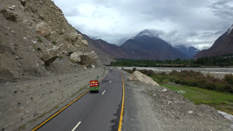 Dramatischer-Drohnenschuss,-Der-Ein-Tuk-Tuk-Auf-Dem-Karakoram-Highway-Pakistan-Entlang-Des-Hunza-Flusses-Jagt