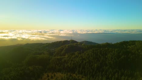 Aerial-approaching-flight-over-green-area-of-Madeira-and-antenna-in-background-with-flying-clouds-at-golden-sunset