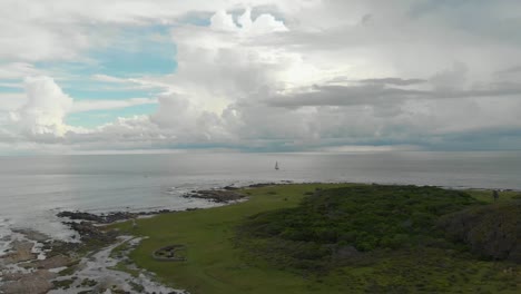 Drone-Volando-Sobre-Una-Isla-Con-Un-Barco-Navegando