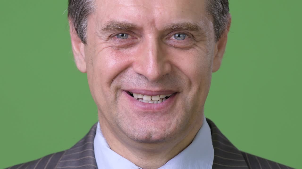 hombre de negocios maduro y guapo contra un fondo verde