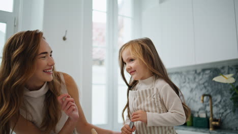 Laughing-mother-touching-daughter-nose-kitchen-close-up.-Cute-family-having-fun