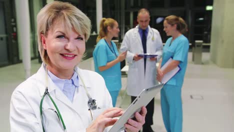 smiling female doctor using digital tablet in hospital corridor