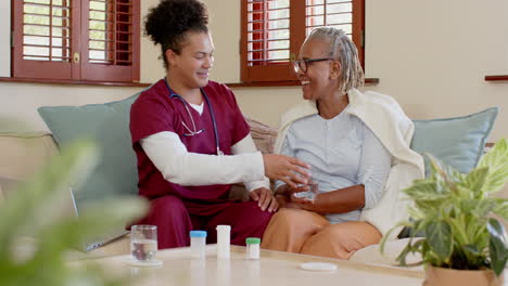 assisting senior woman with laptop, caregiver discussing medication management at home