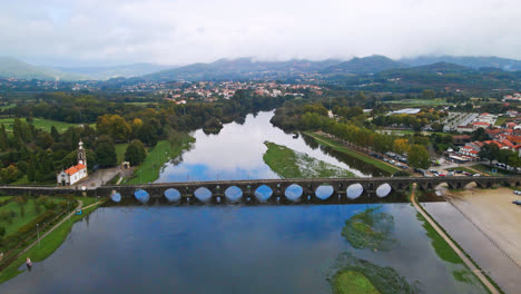 Stunning-aerial-4K-drone-footage-of-a-village---Ponte-de-Lima-in-Portugal-and-its-iconic-landmark---Stone-roman-bridge-crossing-over-the-Lima-River