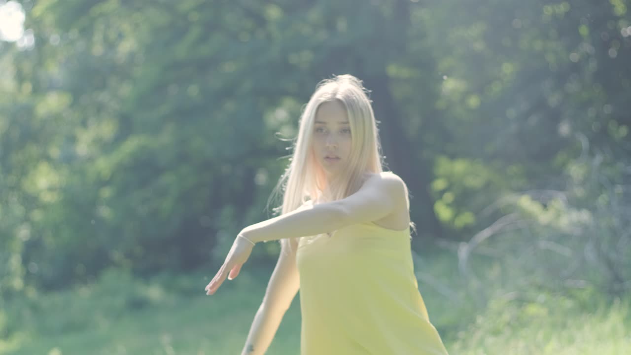 夏の公園で優雅に踊っている黄色いドレスの女性