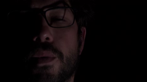 retrata a un joven con gafas y barba, fumando, copiando espacio, fondo negro, de cerca