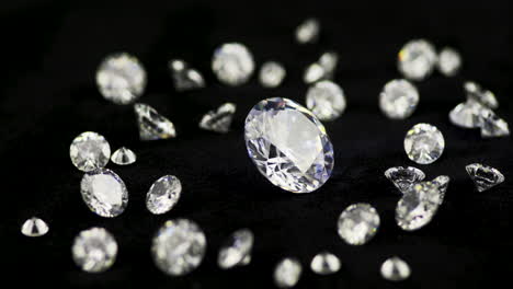 real big brilliant-cut glittering diamond surrounded by the smaller ones rotating clockwise in shallow depth of field on the black table - cinematic selective focus shot