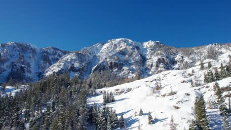 Beautiful-panning-drone-shot-of-a-snow-covered-mountainside-with-trees