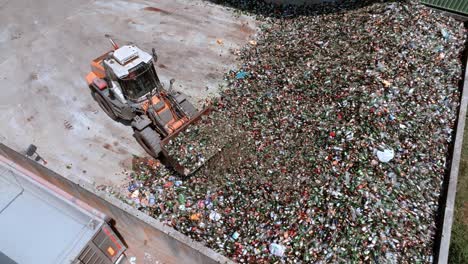 gabelstapler packt glas im lager, schwerlastmaschine hat einen langen arm, der mit einem glaspacker ausgestattet ist, drohnenansicht tagsüber, glasrecyclingkonzept