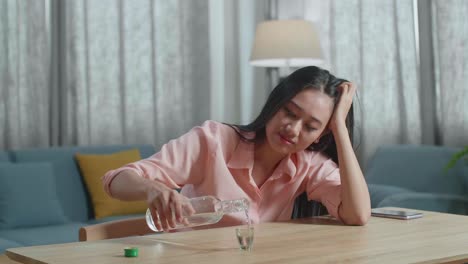 술에 취한 아시아 여성이 보드카를 마시며 집에서 카메라를 쳐다보고 있습니다.