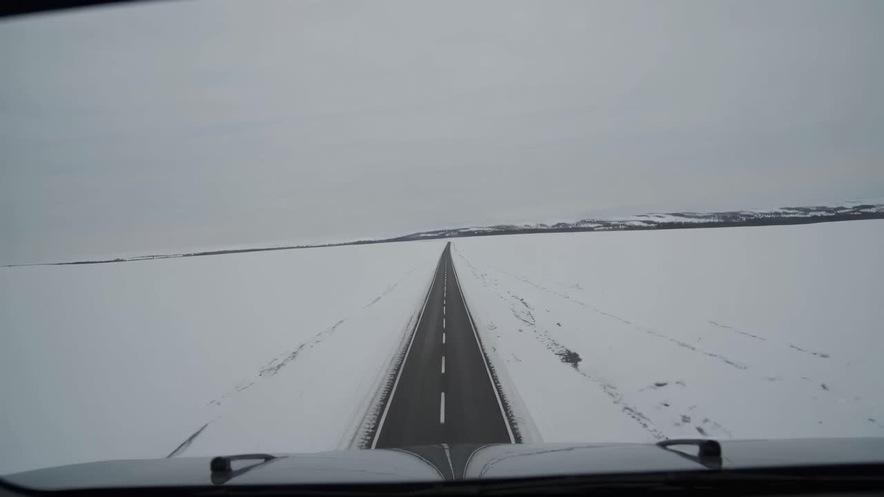 A video captures a wide-angle view from a vehicle dashboard, showcasing a long, straight road