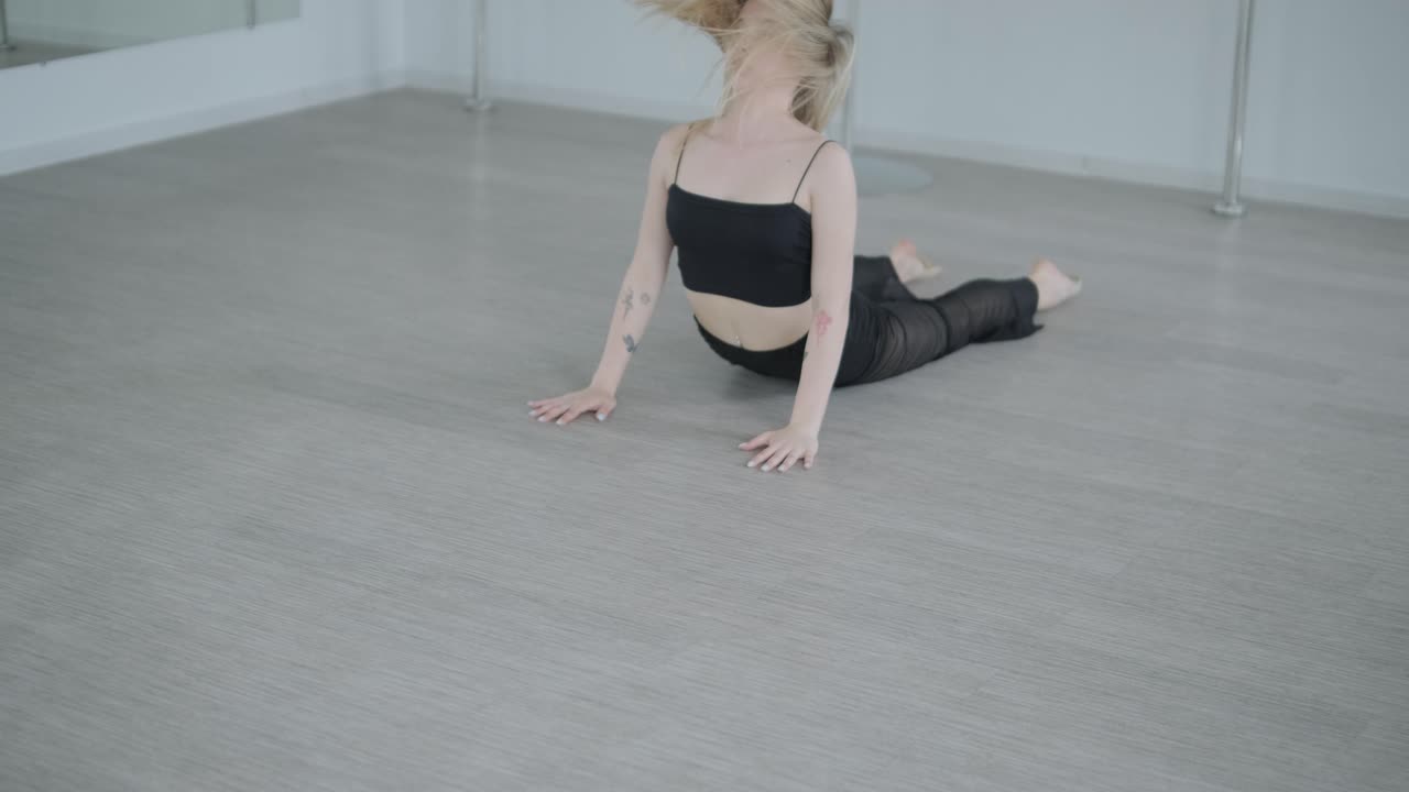 chica en forma con ropa negra actuando contemporáneamente. bailarina muestra movimientos fluidos, cuerpo y manos ondas en la habitación blanca. coreografía de danza de ballet moderno. joven se mueve suavemente