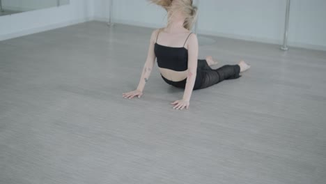 fit girl in black clothes performing contemporary. female dancer shows flowing motions, body and hands waves at white room. modern ballet dance choreography. young woman is moving smoothly