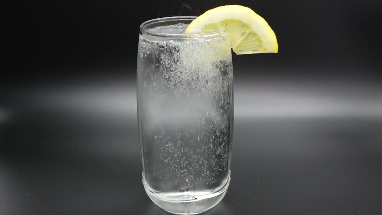 verter agua mineral en un vaso con una rodaja de limón