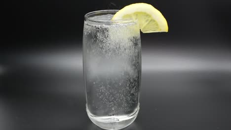 pouring mineral water into a glass with lemon slice