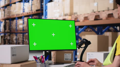 logistics worker manages orders next to green screen display