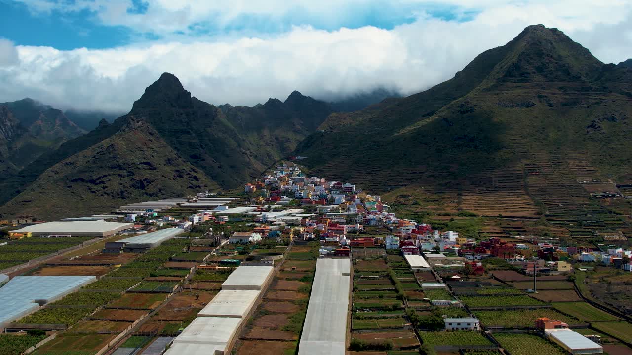 colorido pueblo de montaña con grandes montañas majestuosas en el fondo y espesas nubes blancas