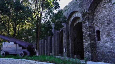 Waffe-Vor-Hohen-Steinmauern-Außerhalb-Der-Historischen-Berühmten-Burg-Von-Gjirokastra