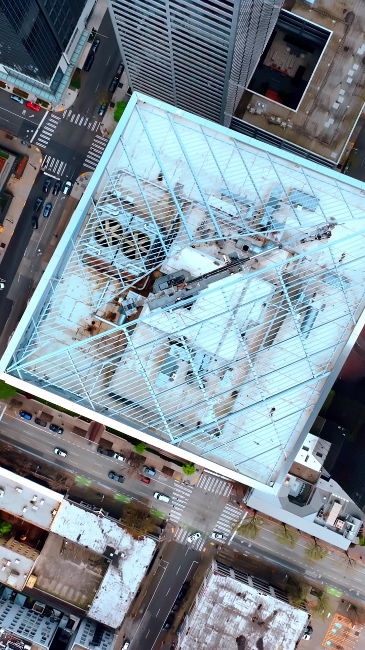 Rising over the top of a square-shaped skyscraper. High-rise buildings are around. Architecture of Seattle, Washington, United States. Vertical video
