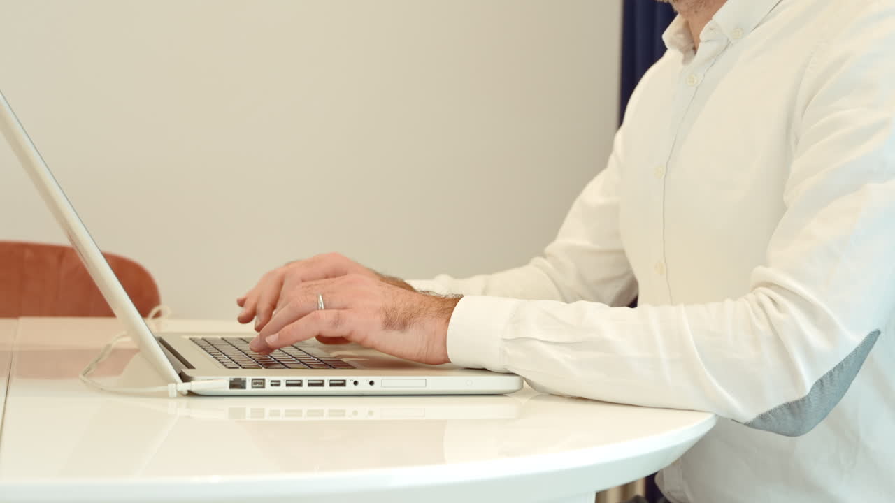 Man wearing white shirt working on notebook at home
