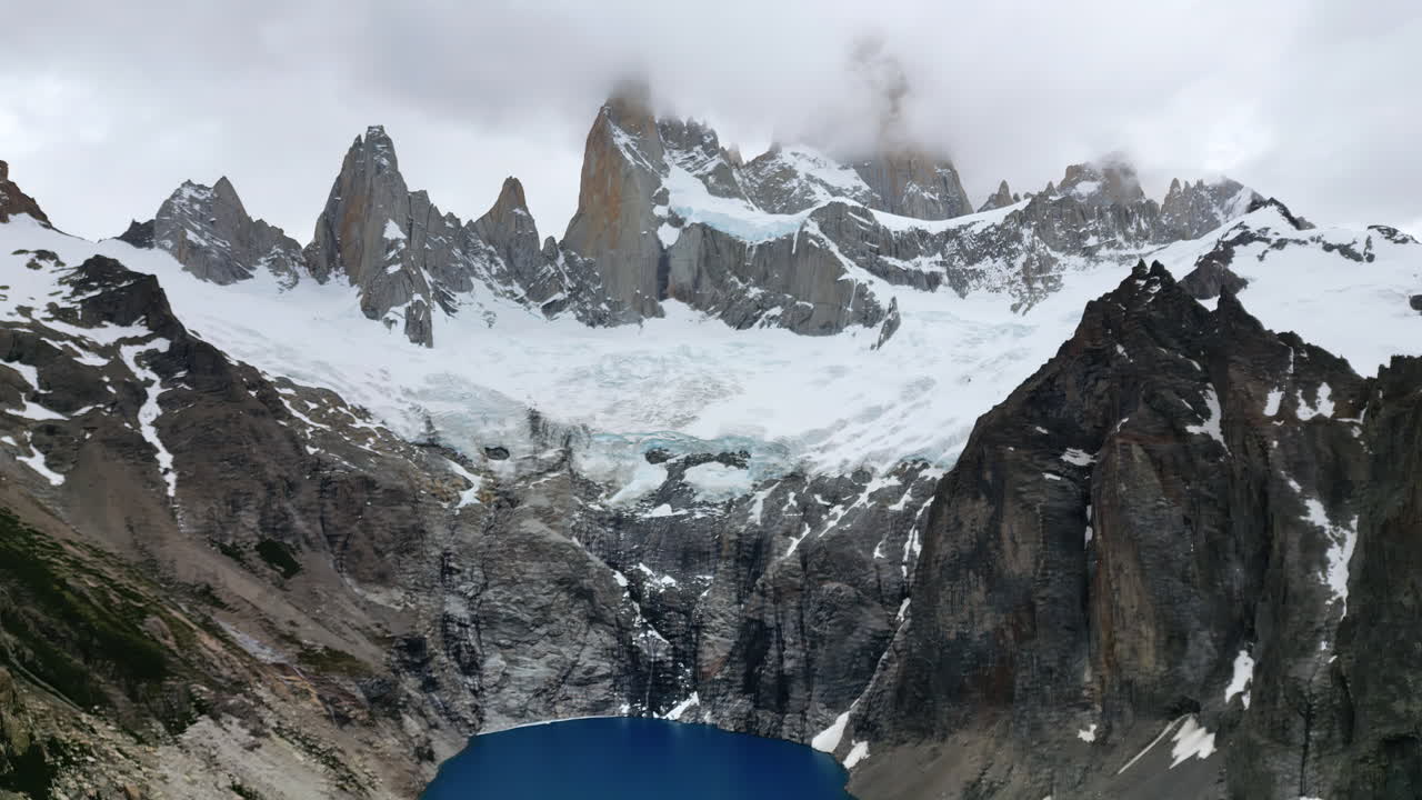 Vista aerea con drone delle spettacolari cime di granito del Fitz Roy parzialmente coperte da nuvole, con ghiacciai che si estendono sui pendii