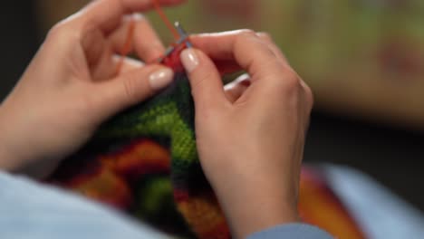 womens hands knit woolen color sweater with knitting needles. top view, close-up of hands and knitting