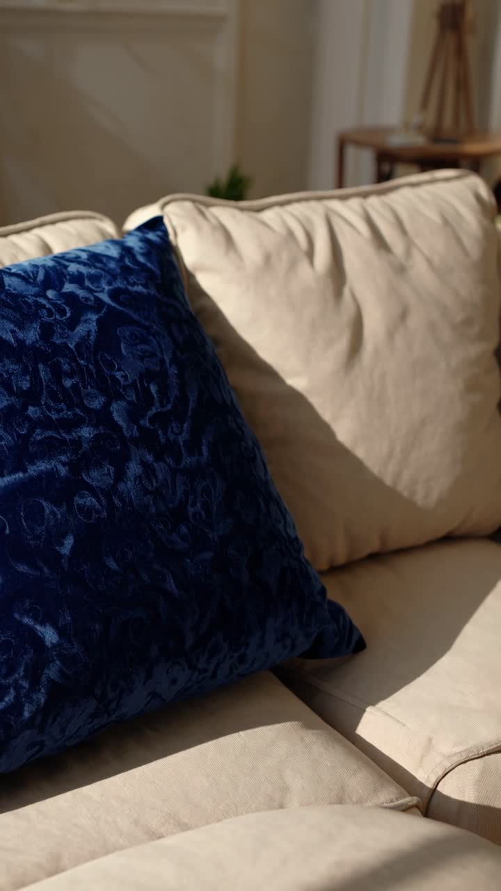 Scena accogliente di un soggiorno con un primo piano su un morbido cuscino blu su un divano beige.