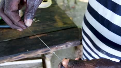 Man-Tying-A-Fishing-Hook-And-Line-On-A-Tropical-Island-in-Bougainville,-Papua-New-Guinea