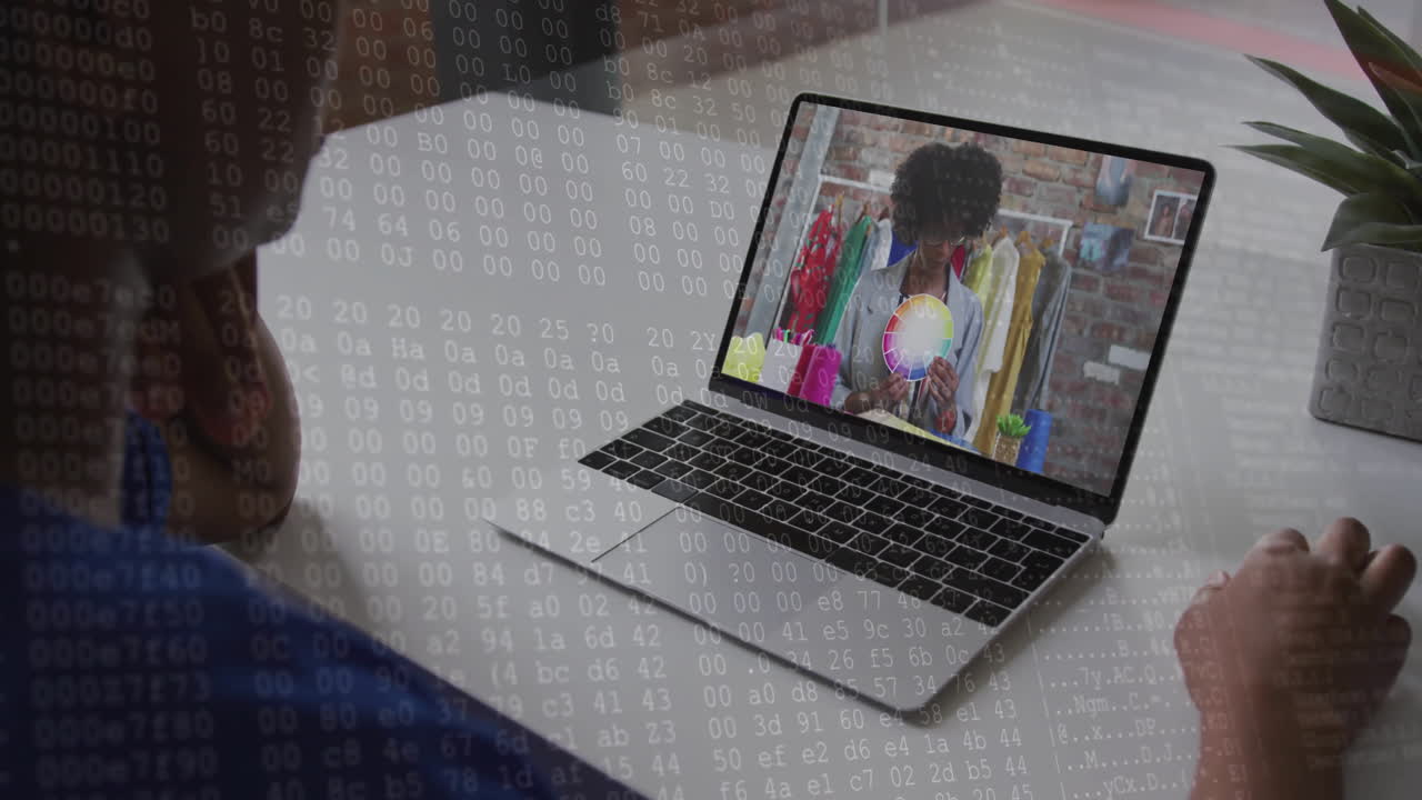 Binary code animation over person watching fashion video on laptop