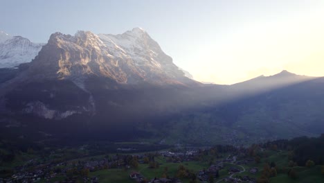 imágenes aéreas de drones dolly de izquierda a derecha sobre el pueblo de grindelwald con vista de la puesta de sol de la cara norte del eiger