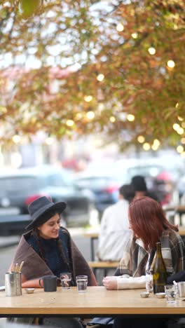 two women enjoying coffee at an outdoor cafe in autumn