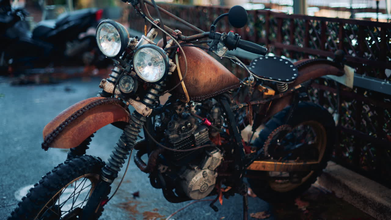 Close up of a vintage rusty motorcycle parked on a city street