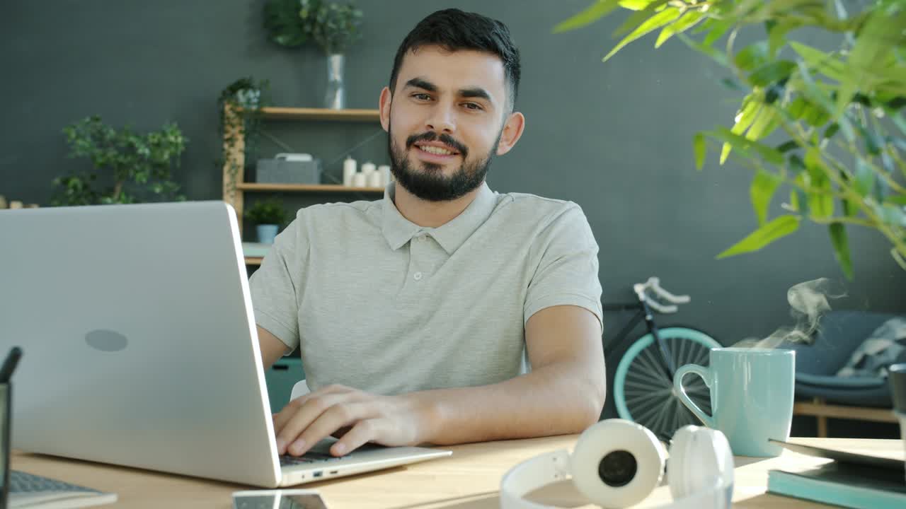 retrato en bucle de cinemagraph de un joven independiente alegre trabajando con una computadora portátil en casa